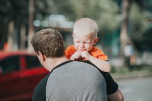 A father carrying his crying child to his red car in Las Vegas.